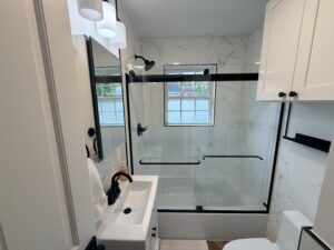 Natick bathroom renovation full view - vanity, matte black faucet and sliding glass tub shower enclosure